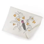 Un torchon de cuisine en coton absorbant, imprimé colibri, est suspendu avec soin à une poignée de four moderne.