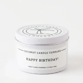 Jar of Coconut Candle Company Happy Birthday Candle with minimalist label next to birthday decor