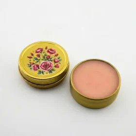 Close-up of open Blooming Wild True Rose Balm gold tin showing natural rose salve texture on white background