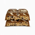 Close-up of a broken Astro Snacks Cookies & Cream Dubai Chocolate Bar showing the cream and cookie filling against a pure white background