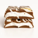 Close-up of a broken Astro Snacks Cookies & Cream Dubai Chocolate Bar showing the cream and cookie filling against a pure white background